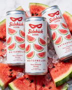 Three chilled Sidekick Watermelon cans on ice with fresh watermelon wedges on white marble